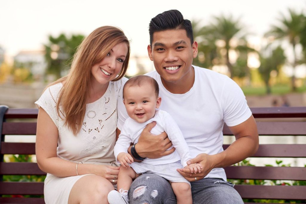 Smiling couple sitting outdoors with their baby