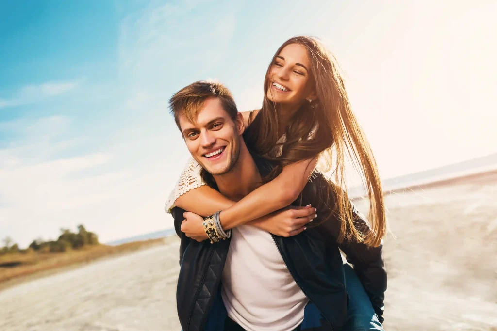 Young man giving a young woman a piggyback ride outdoors
