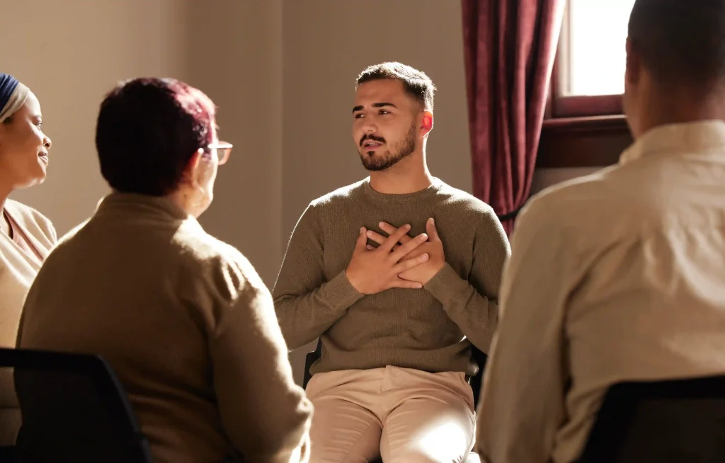 Man speaking with his hand on his chest during a group therapy session