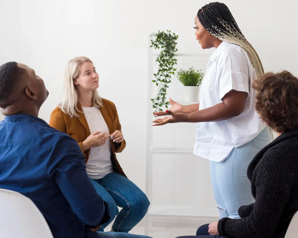 Group seated together while a woman holds a potted plant