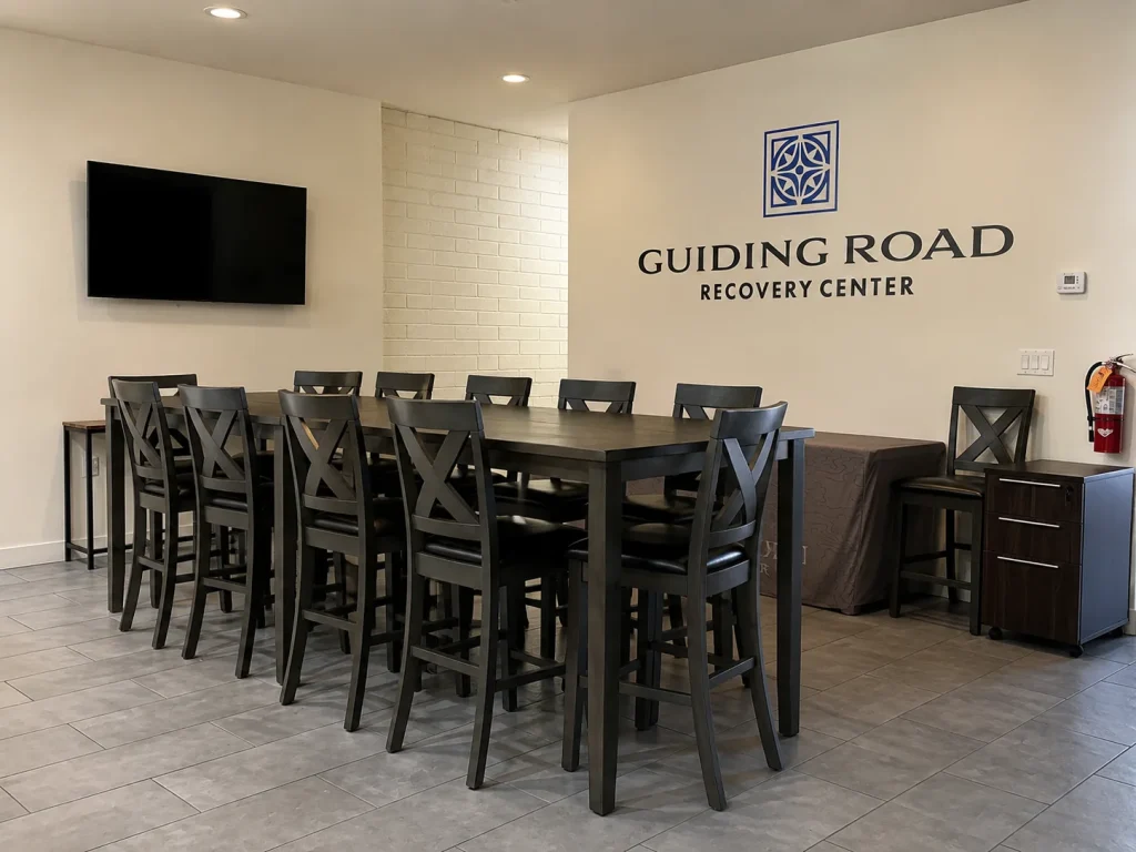 Community dining area with a high-top table and the Guiding Road Recovery Center sign