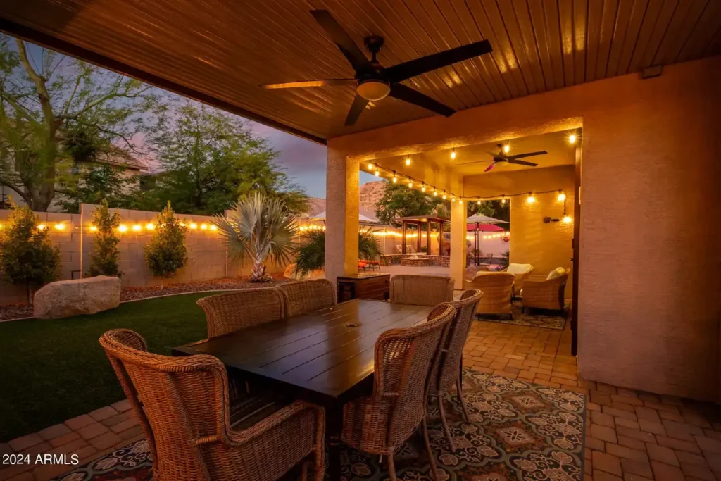 Covered patio with a dining table and string lights at dusk